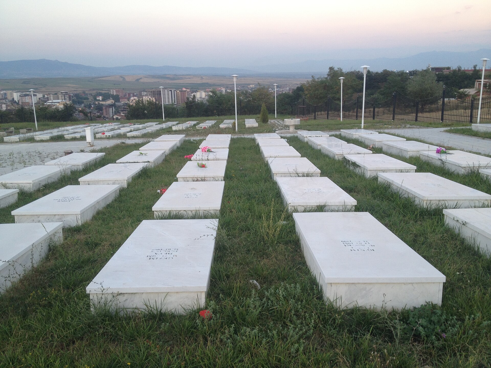 Gedenkstätte und Friedhof für Opfer des Kosovokriegs in Gjakova. Bdx, eigene Aufnahme, 28. Juli 2015. Via Wikimedia Commons. Konfliktkontext; kein Nachweis schweizerischer Waffen oder einer konkreten Tat. Lizenzprüfung: 26.09.2026. Gedenkstätte und Friedhof für Opfer des Kosovokriegs in Gjakova. Bdx, eigene Aufnahme, 28. Juli 2015. Via Wikimedia Commons. Konfliktkontext; kein Nachweis schweizerischer Waffen oder einer konkreten Tat. Lizenzprüfung: 26.09.2026.